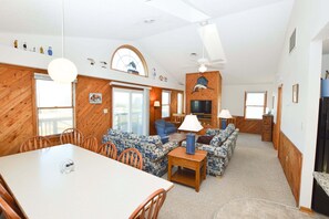 A spacious living area with a dining table, sofas, a TV, and a ceiling fan. - This home is nicely decorated, well maintained and offers something for everyone in the family. (South Nags Head)