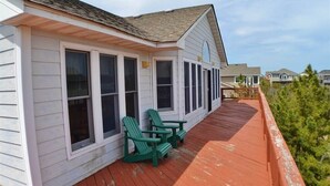 A house with a covered porch and two green Adirondack chairs. - When it is time to Set Back & Relax, you have found the vacation rental home to do just that. (Corolla)