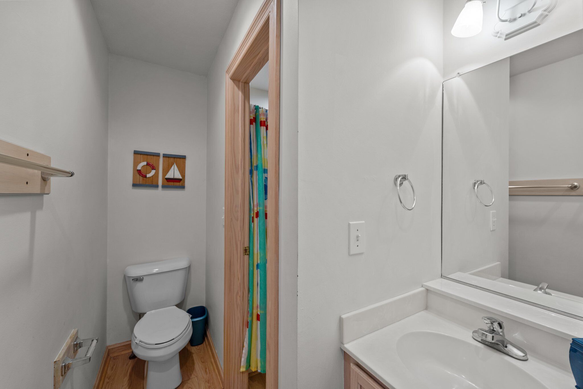 Een badkamer met toilet, wastafel, spiegel en houten deur.