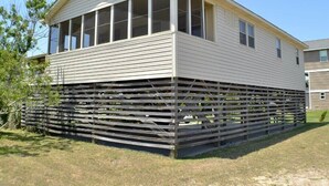 A single-story mobile home with a gabled roof and large windows on the upper floor. - Just across the street from the beach, “Pope” is perfect for a small family. (South Nags Head)