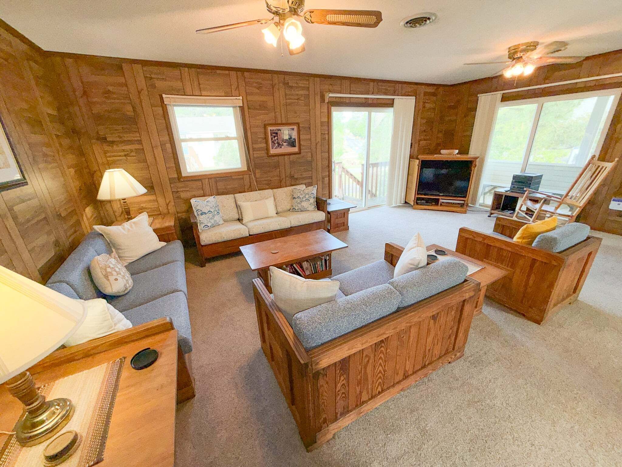A cozy living room with wooden walls, a sofa set, a coffee table, and a TV.