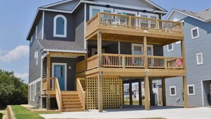 A two-story house with a wooden deck and a front porch. - Charming Outer Banks Home (Kill Devil Hills)
