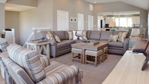 A spacious living room with a sectional sofa, a coffee table, and a ceiling fan. - Charming Outer Banks Home (Kill Devil Hills)