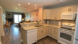 Une cuisine moderne avec des meubles blancs, un lave-vaisselle, une cuisinière et un four à micro-ondes.