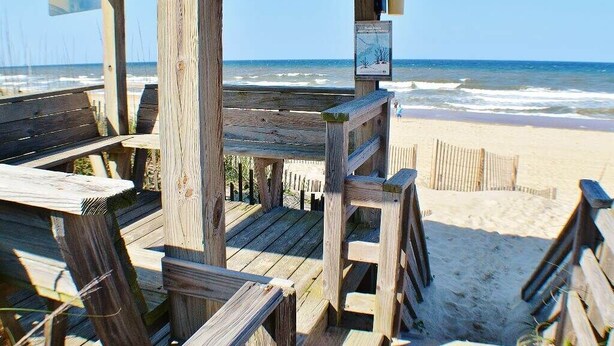 A wooden beach deck with a view of the ocean.