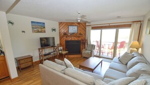 A living room with a sofa, television, fireplace, and a view of the outside.