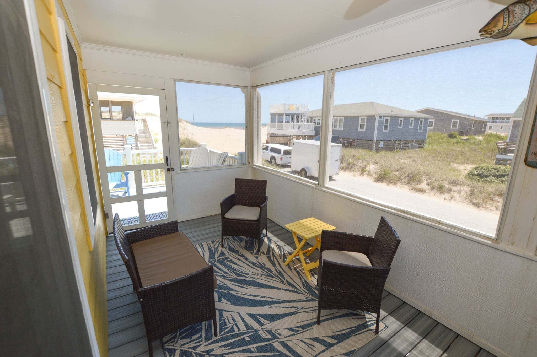 A room with a view of the beach, wicker furniture, and a small table.