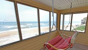 A wooden interior with large windows overlooking a beach. - This charming beach house is the perfect year-round retreat. (South Nags Head)