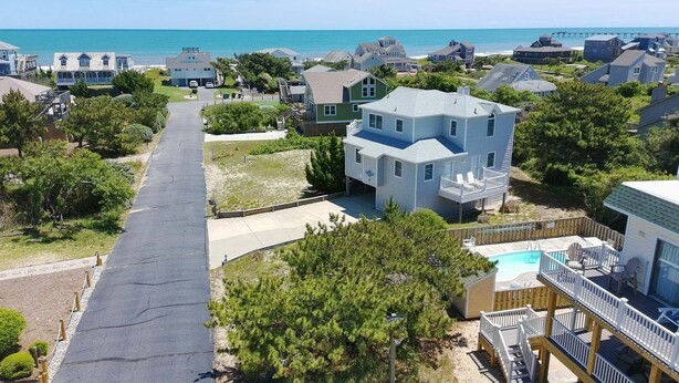 A residential area with houses, a driveway, and a view of the ocean.