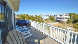 A wooden deck with outdoor furniture, a white railing, and a view of neighboring houses.