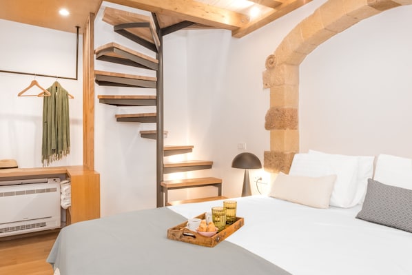 A hotel room with a bed, a tray with snacks, a staircase, and a wall-mounted towel rack.
