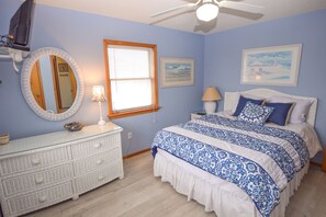 Un dormitorio con cama, cómoda y ventilador de techo.