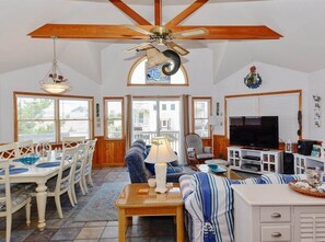 A spacious living room with a ceiling fan, a dining area with a table and chairs, a sofa, a television, and a fireplace. - Private pool with direct Beach Access (Kill Devil Hills)