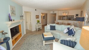 A living room with a fireplace, a sofa, a coffee table, and a television. - Great condo in Duck, NC (Duck)