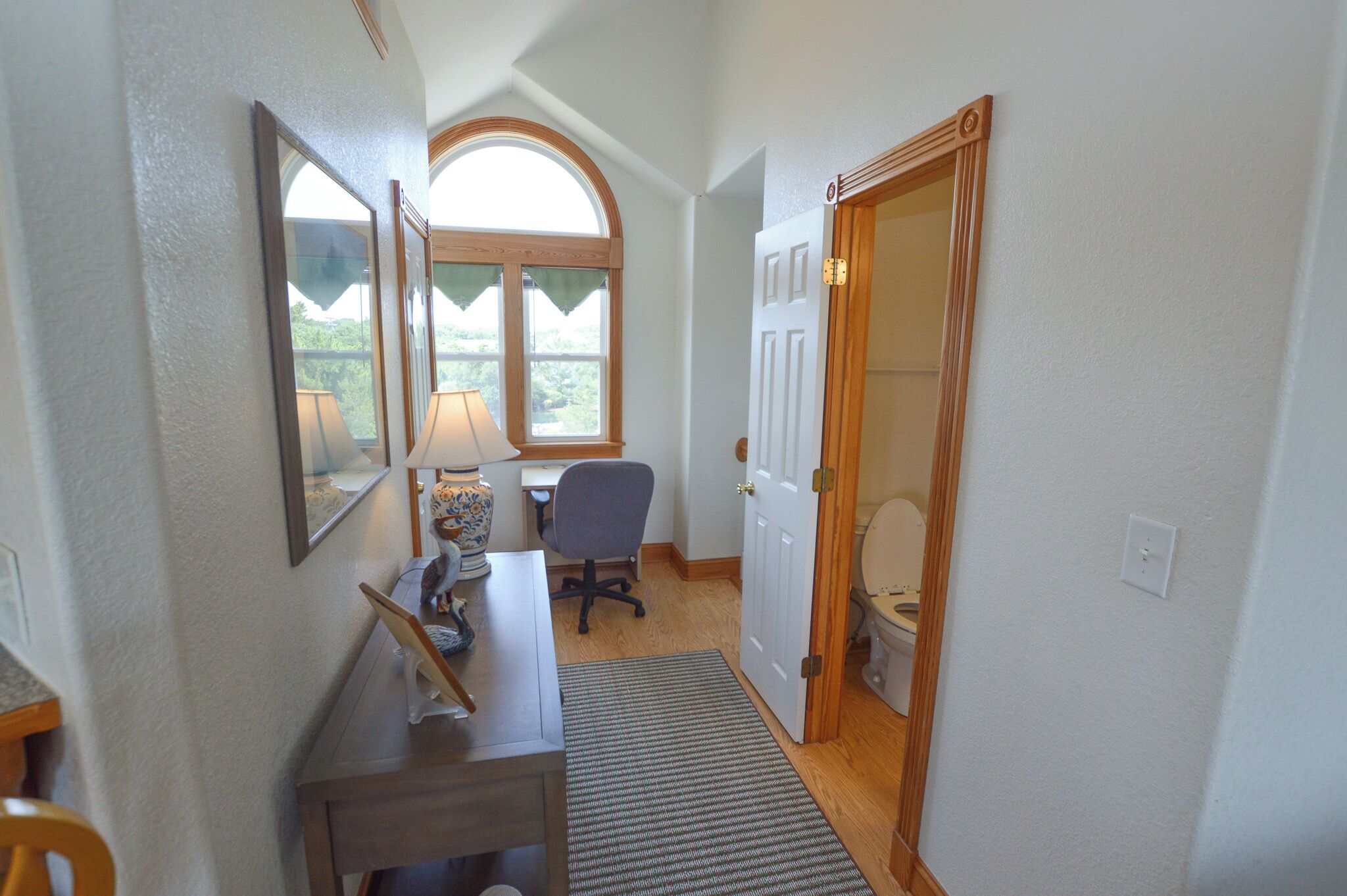 Un couloir étroit avec un bureau, une chaise et une porte donnant sur une salle de bain.