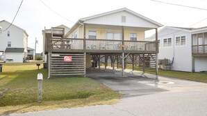 A two-story building with a covered walkway and a small parking area. - Pet Friendly on Outer Banks. (Kill Devil Hills)