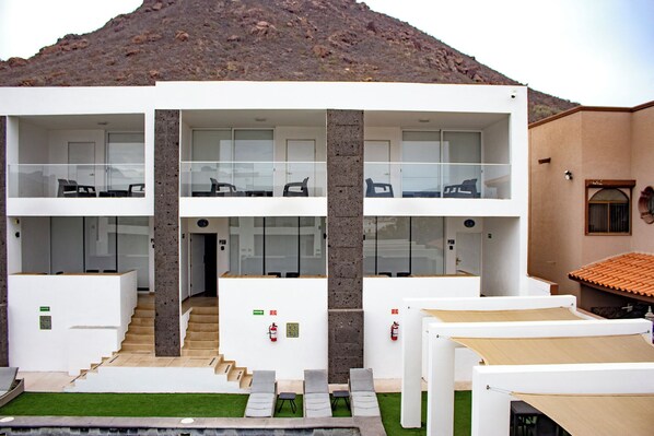 A modern two-story building with a flat roof, large windows, and a staircase leading to the upper floor.