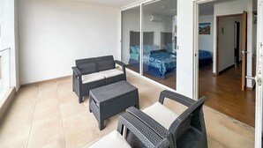 A balcony with wicker furniture, a sliding glass door leading to a bedroom, and a ceiling light. - Turquesa 1 Joyas del mar San Carlos (San Carlos)