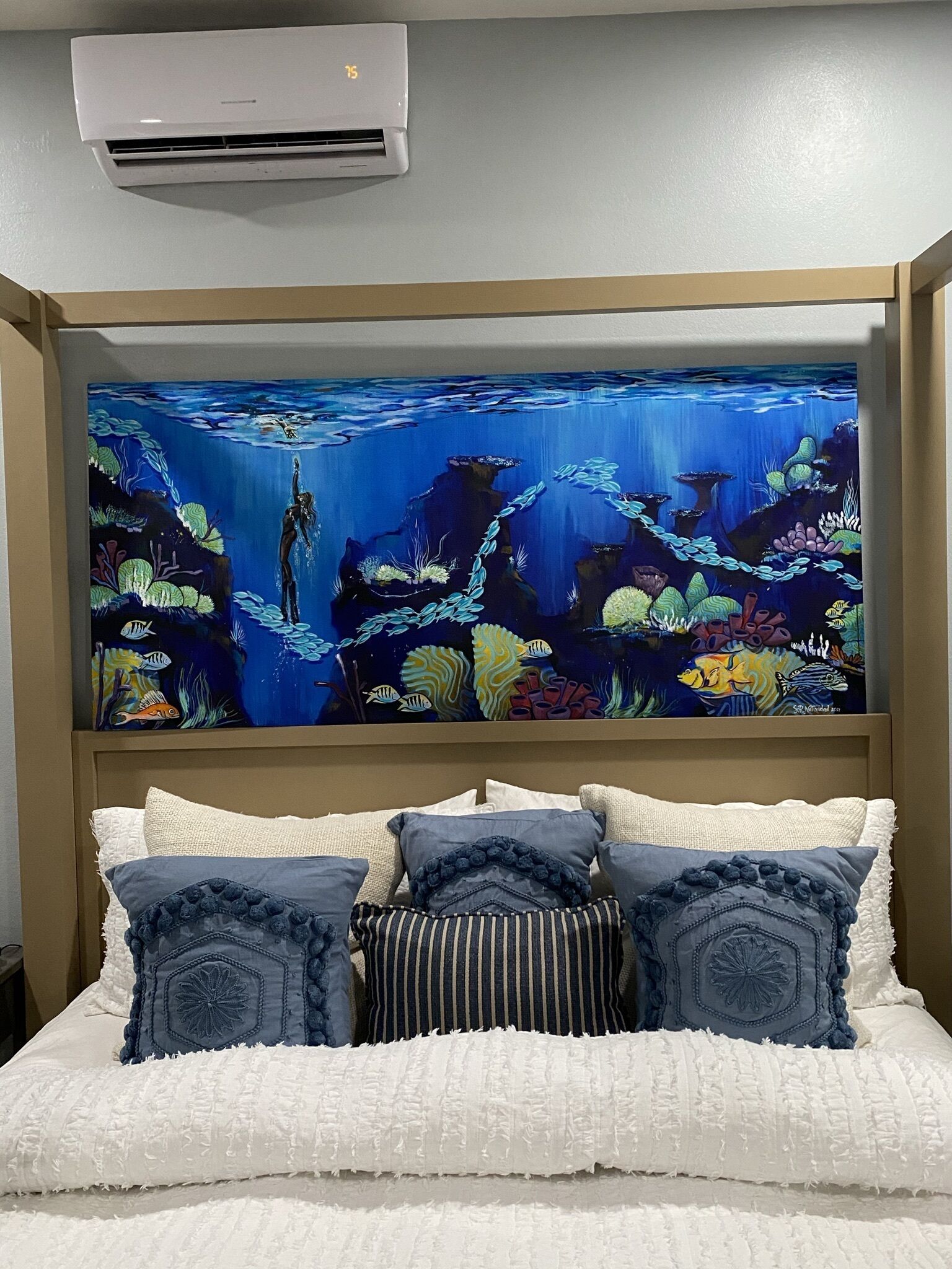 A bedroom with a large wall mural of an underwater scene, a bed with white bedding, and a brown headboard.