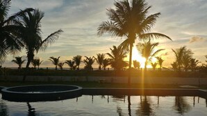 En pool med palmer og en solnedgang i baggrunden.