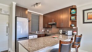 A modern kitchen with granite countertops, stainless steel appliances, and wooden cabinets. - Quayside 1206by CTHA (Cape Town)