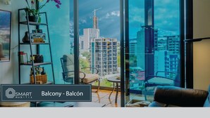 Un salon moderne doté d’une grande fenêtre donnant sur la ville, d’une bibliothèque et d’un coin salon confortable.