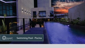 Un bâtiment moderne doté d’une piscine, offrant une vue sur le coucher de soleil et comprenant un espace extérieur aménagé.