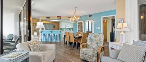 A spacious living room with a sofa, armchair, and a dining area with chairs and a table.