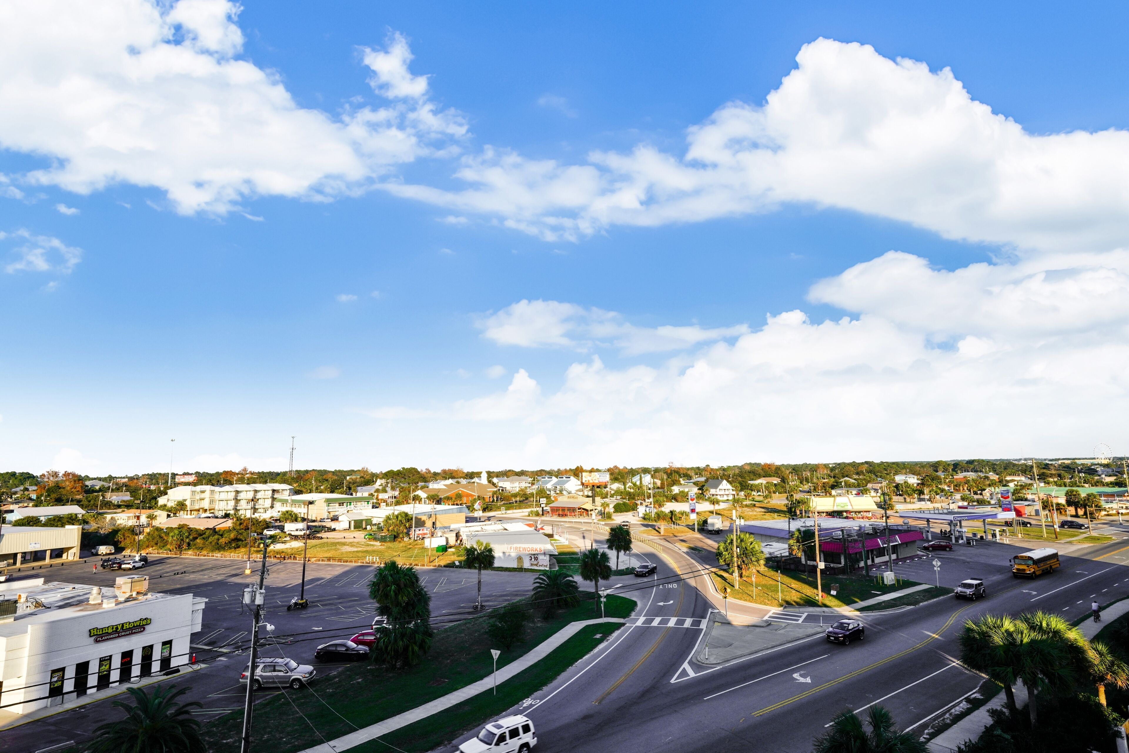 A wide-angle view of a town with a large intersection, multiple roads, and buildings including a gas station.