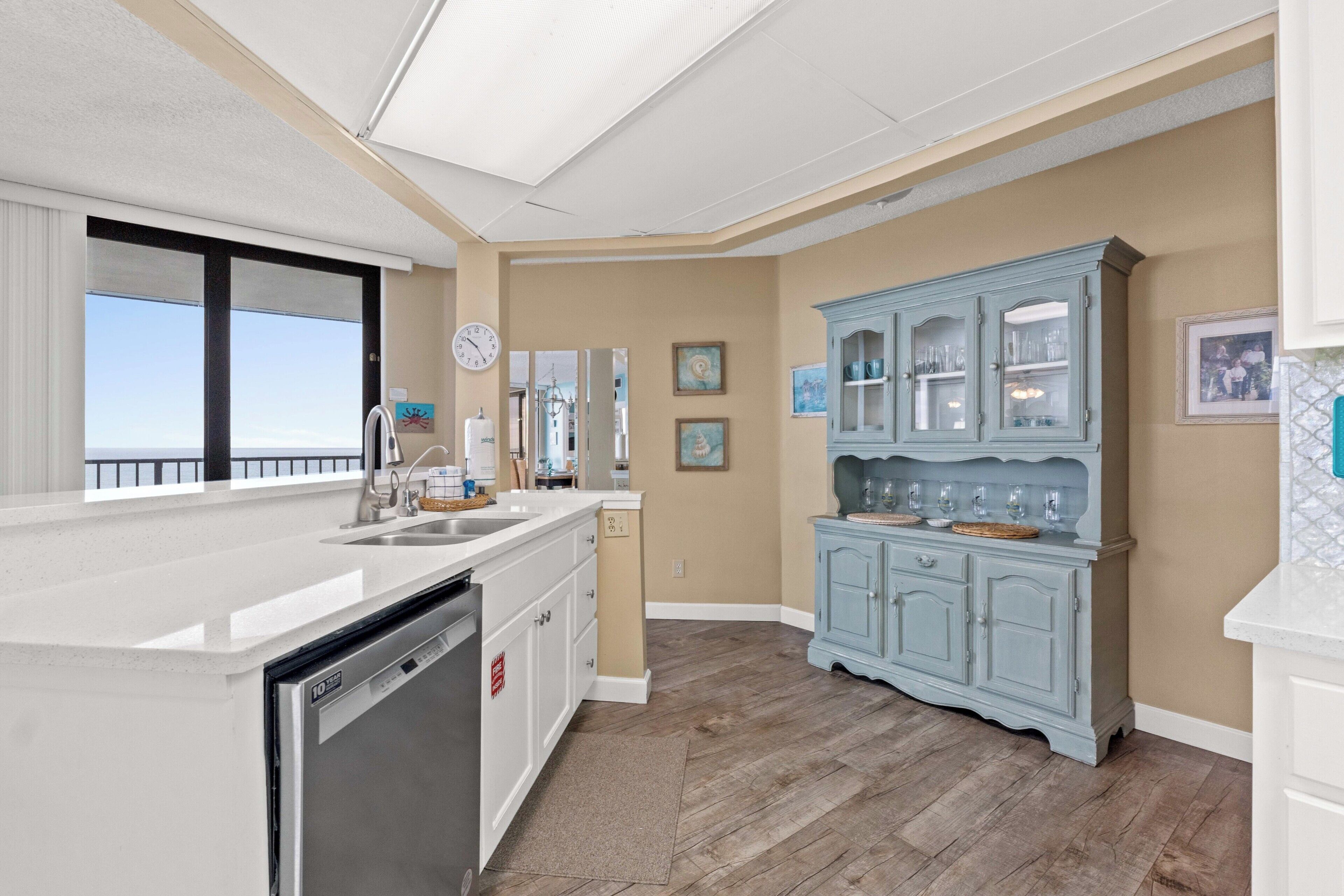 A kitchen with a large island, a blue cabinet, and a view to the outside.