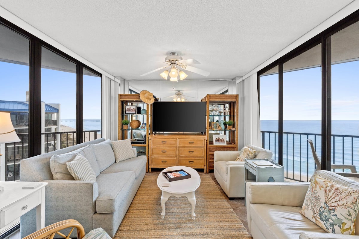 A spacious balcony with a sofa, armchairs, a coffee table, and a TV.