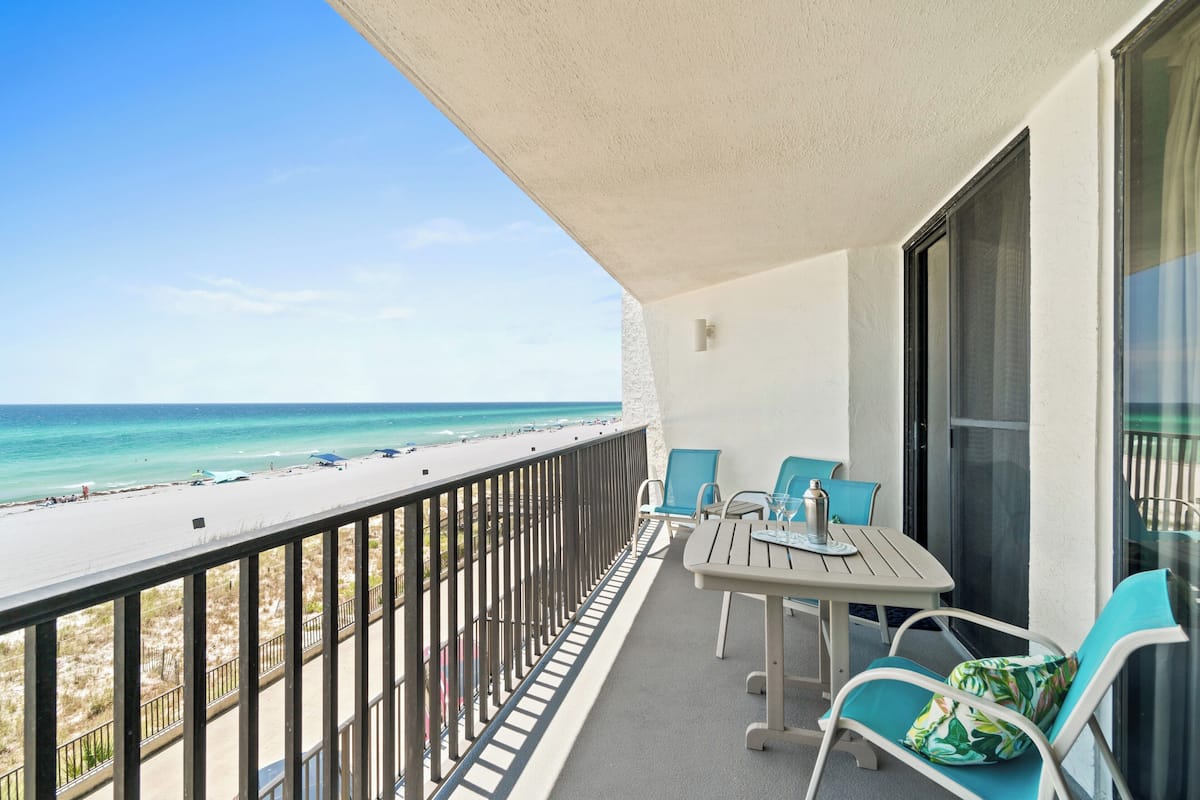 A balcony with a view of the beach and ocean.