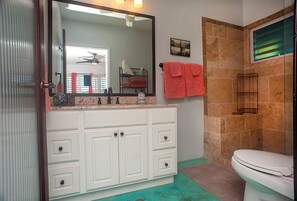 Un baño con tocador blanco, un espejo grande, un inodoro y una zona de ducha.