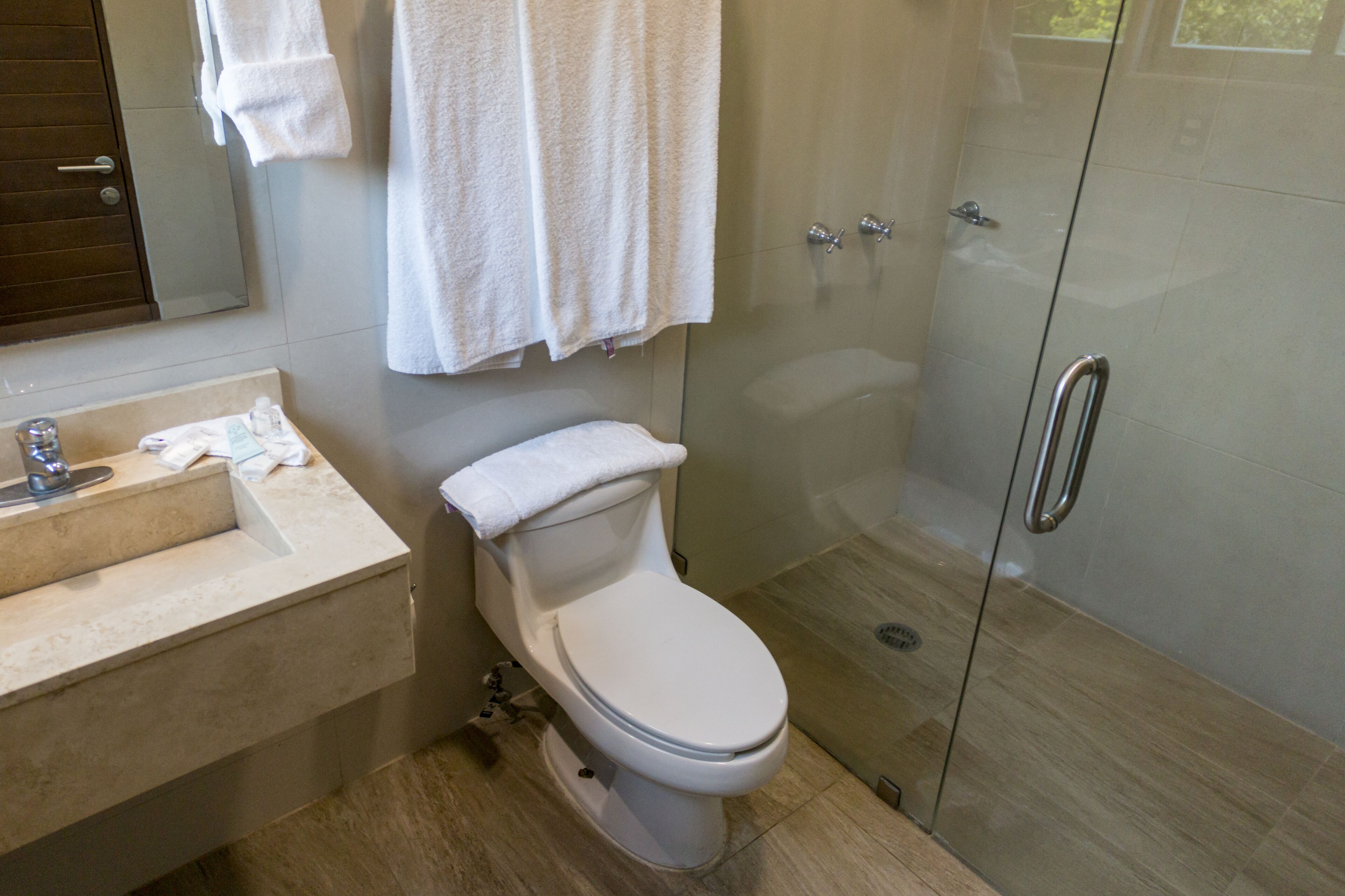 Un baño moderno con inodoro, lavamanos y cabina de ducha de vidrio.