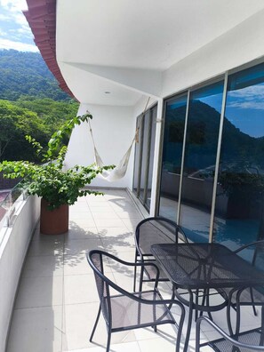 A balcony with a hammock, a potted plant, and a table with chairs. - La Loma Suites (Ixtapa)