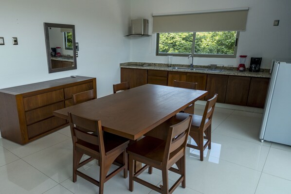 A kitchen with a wooden table and chairs, a window with a view of greenery, and a built-in oven.