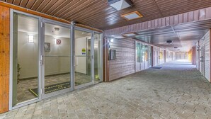 Um corredor com teto de madeira, portas de vidro e chão de azulejos.