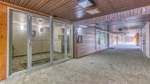 Käytävän lattia on tehty tiilistä, katto on puuta ja huoneeseen johtavat lasiovet.