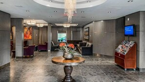 A modern lobby with a round table, seating area, and a television on the wall. - Beautiful 2 Bed 2 bath Pool Waterslide & Hot tubs (Canmore)