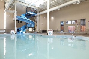 Una piscina interior con un tobogán de agua azul y un letrero de precaución.