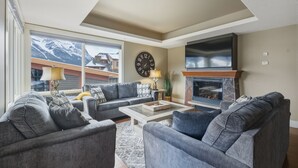 Een woonkamer met een open haard, een grote klok en een zithoek.