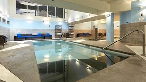 A swimming pool with a glass bottom, surrounded by seating areas and a high ceiling. - Star Suite 2 Bed 2 bath condo with 3 fireplaces (Canmore)