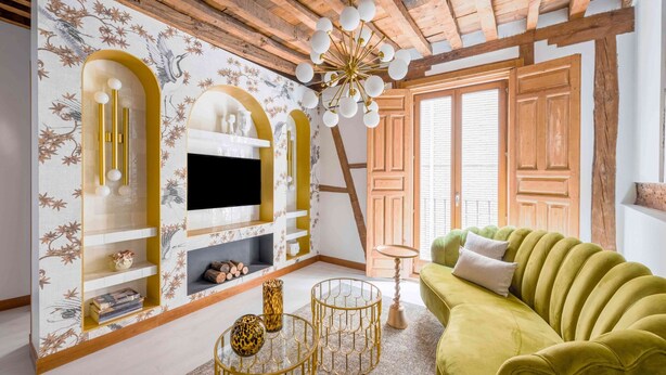A living room with a green sofa, a fireplace with a TV, and wooden beams on the ceiling. - ~TROPIC~ by myhomeintoledo.com (Toledo)