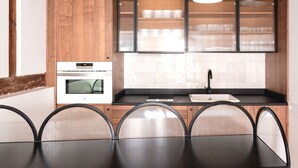 A modern kitchen with a built-in oven, a sink, and a dining area with a table and chairs. - ~TROPIC~ by myhomeintoledo.com (Toledo)