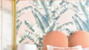 A bedroom with a bed, a nightstand, a lamp, and a wall with a leaf pattern. - ~TROPIC~ by myhomeintoledo.com (Toledo)