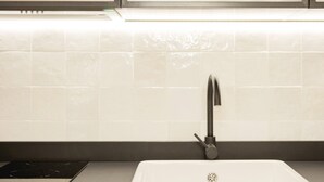 A modern kitchen with a sleek black faucet, a white sink, and a black induction cooktop. - ~TROPIC~ by myhomeintoledo.com (Toledo)