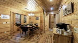 Un interior de madera con una mesa de comedor, sillas, una araña y un letrero que dice 'Eat Drink All be thankful'.