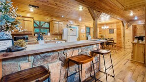 Un interior de madera con mostrador de piedra, taburetes de bar, electrodomésticos de cocina y armarios de madera.
