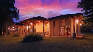 Een huis met twee verdiepingen, een overdekte patio, een groot raam en een deur met rasterwerk.
