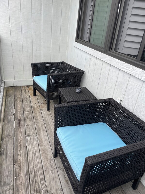 A small outdoor seating area with wicker furniture and a wooden deck. - Studio Villa on 30A - easy beach access! (Santa Rosa Beach)